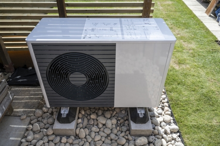 Front view of the air source heat pump outside in the garden.